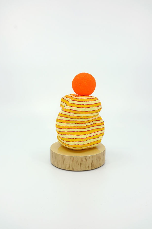 Orange and yellow striped sculpture with an orange sphere on top of it