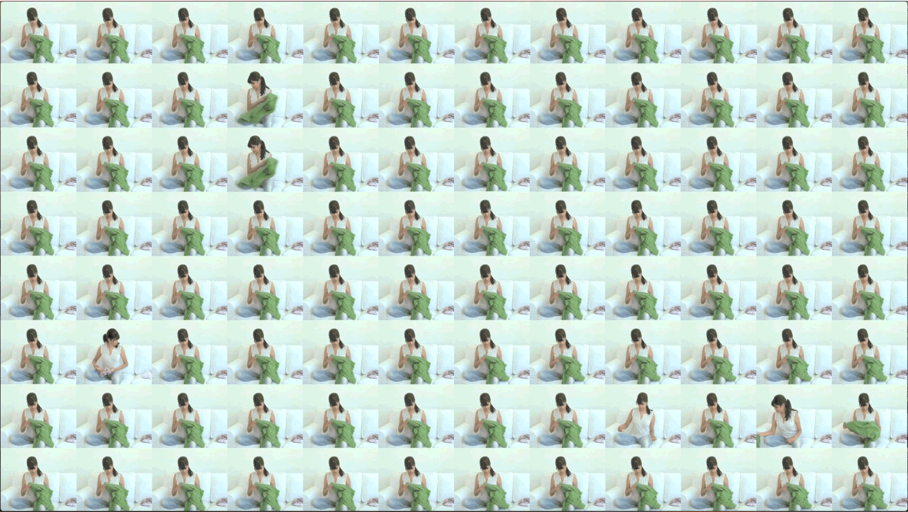 96 video frames arranged in an eight-by-twelve grid. In each frame, Surabhi Saraf is seated on a white couch folding green laundry. The video plays on the frames in a coordinated manner to create patterns of movement within the grid.