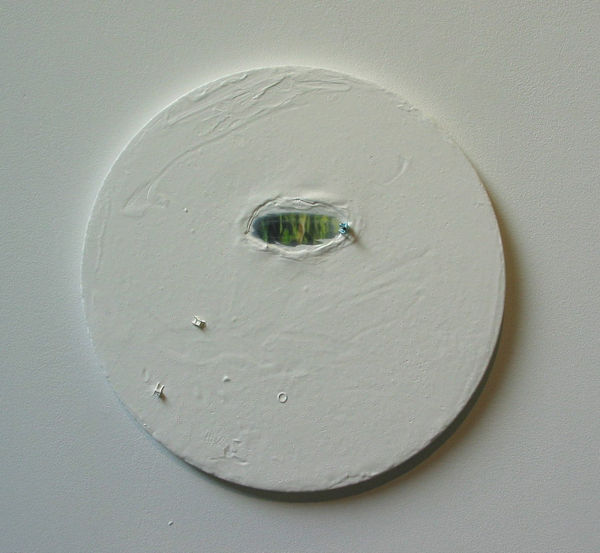 Thickly layered and textured white paint covers a circular canvas. At the upper center of the canvas the paint appears to be pushed back in an uneven oval shape to reveal a yellow green and blue watery surface. A tiny figurine stands on the edge between the white canvas and the multicolored watery surface