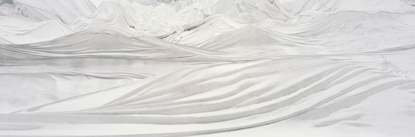 Digital panoramic landscape photograph of bright white tarps blanketing the rough multiple ridged surface of the Swiss Rhône Glacier during the day