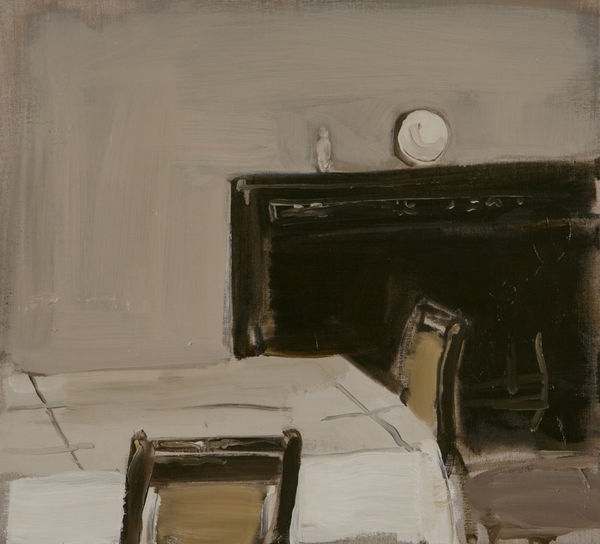 Corner of a table with white table cloth and two chairs in front of black mantelpiece.