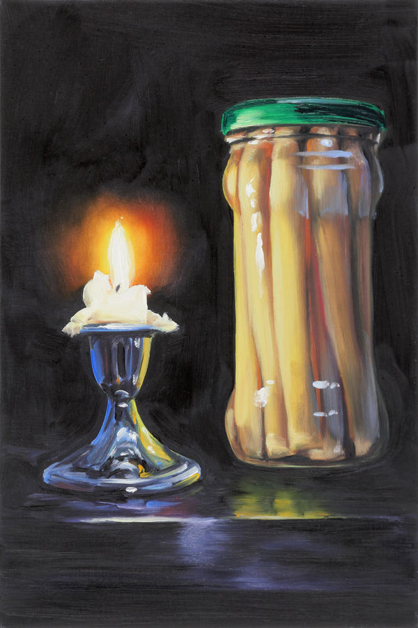 Still life of lit candle to the left of jar of preserved asparagus with green lid.