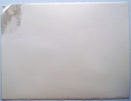 Piece of white rectangular paper in which the upper left corner has been folded and frayed