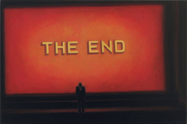 Man in suit stands with head bowed in front of giant red screen with the words “THE END” written in yellow block letters.
