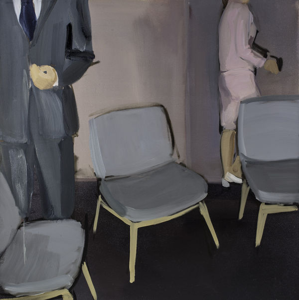 Three chairs in are arranged in circular manner. Behind them stands man in gray suit to the left and woman in pink skirt and coat to the right. The faces of the people are cropped from the composition.