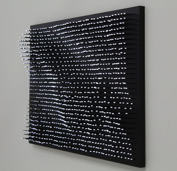Still image of multiple white LEDs at the tips of rods mounted at irregular heights on a black board to form the shapes of waves The LEDs display moving scenes of swimmers