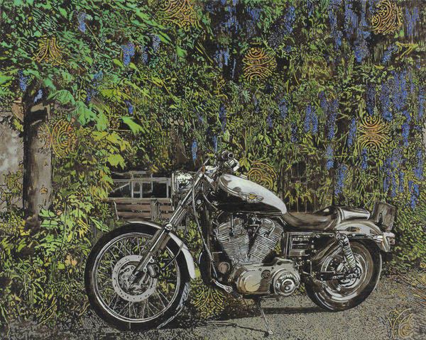 Green leaves and blue flowers hang from tree over parked motorcycle. Circles of ornate abstract pattern peek through the dense foliage.