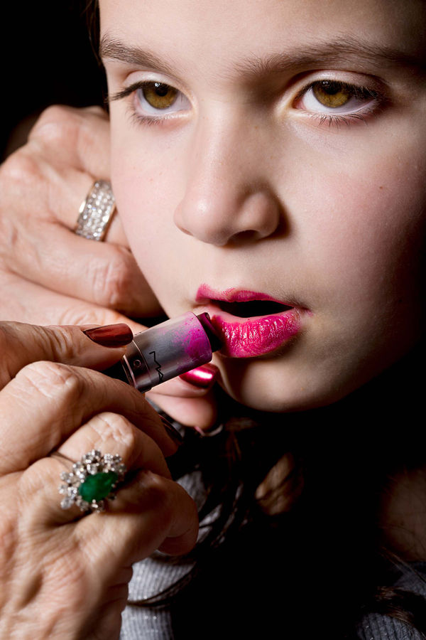 Elinor Carucci close up photograph of her daughter's face with her mother's hands applying lipstick