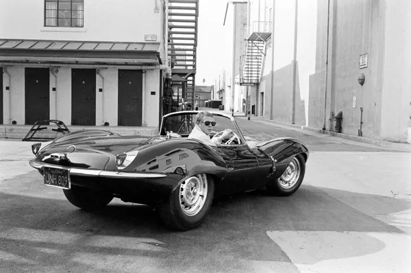 John Dominis, Steve McQueen in black jaguar at studio, CA, 1963