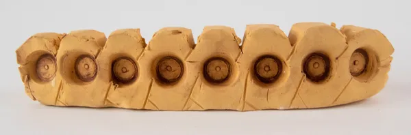 A sculpture of a segmented block with a circular detail in the side of each segment by artist Reniel Del Rosario.