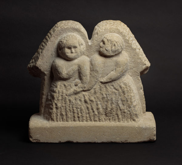Simple sculpture of two people standing next to each other carved into stone.