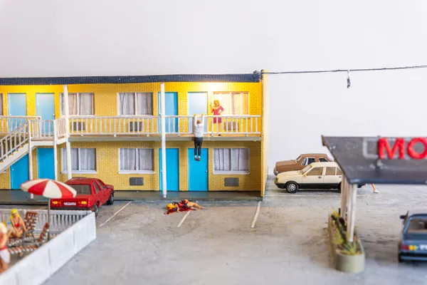 miniature diorama by Abigail Goldman of a woman bleeding on the ground in the parking lot of a motel