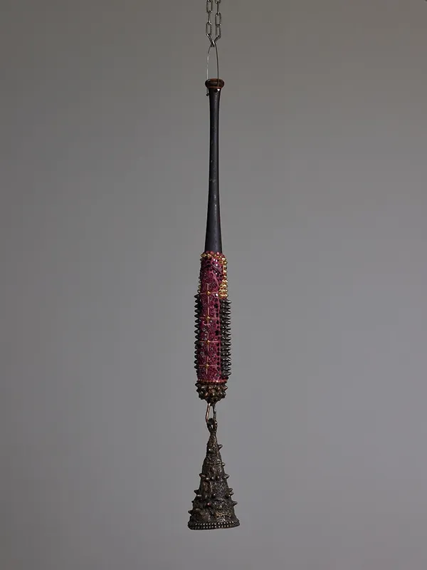 suspended mixed media bat sculpture with a bronze bell hanging at the end by Lucien Shapiro