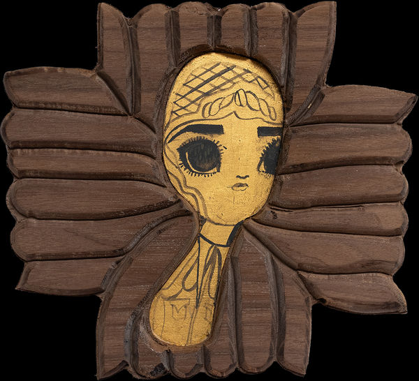 A piece of carved wood with a gold leaf portrait of an illustrative style woman in the center.