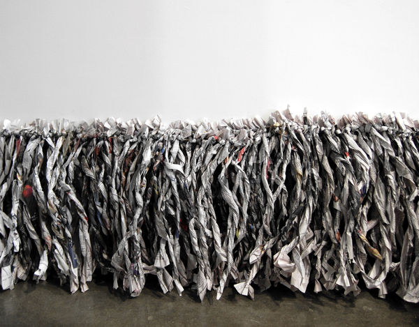 Twisted newspaper strips strung together and lining lower edge of wall touching floor