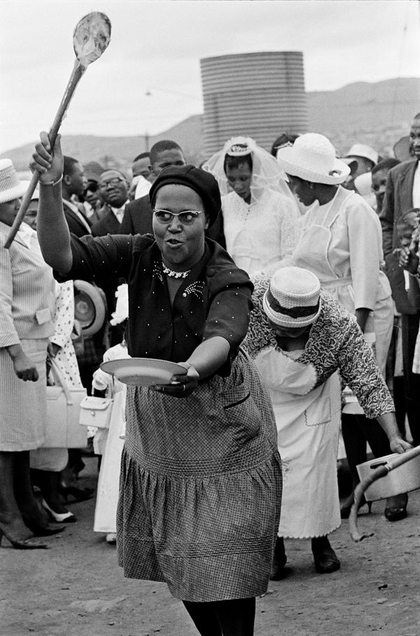 Ernest Cole, Old traditions from a modern wedding. Women greet the couple with symbols of the wife's duties to husband and his family , circa 1965