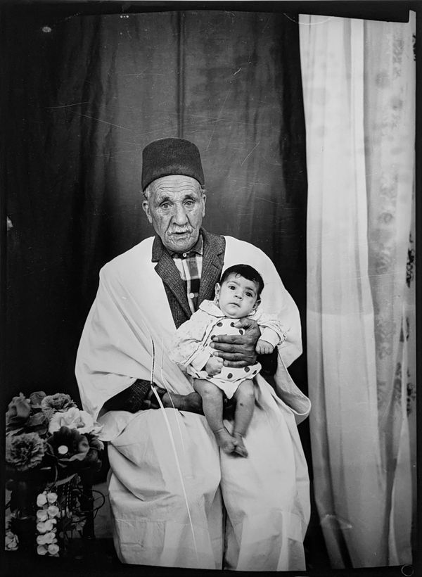 1960s black and white photograph of an older man wearing traditional middle eastern attire holding a small child