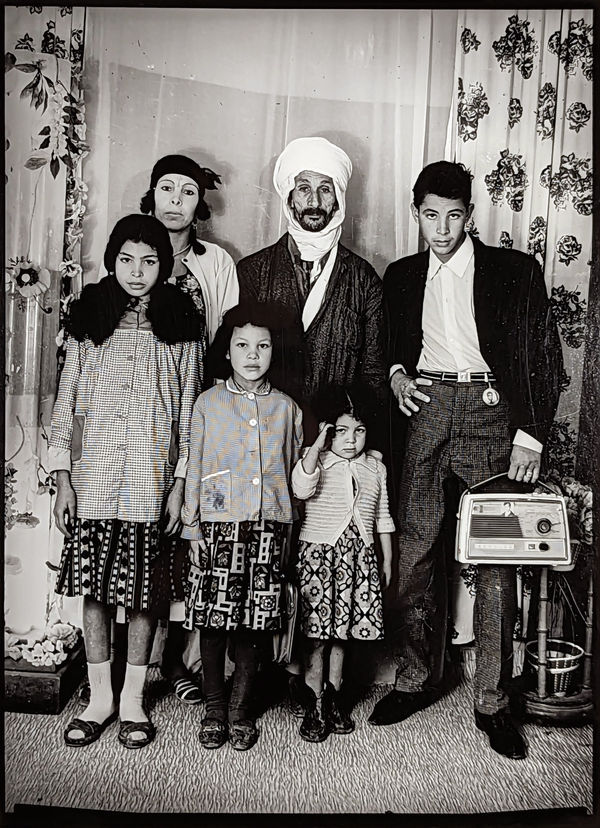 1960s black & white photograph of a family, mother, father and four children, in a photography studio