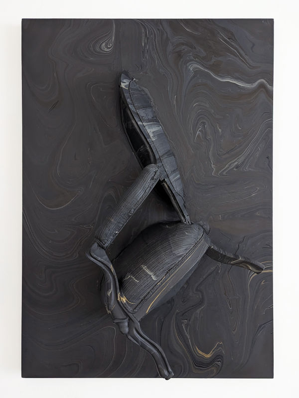 The vertical half of an upholstered chair mounted onto a canvas tipped forward at approximately a 50 degree angle, both with a black swirling marble pattern created by being immersed in acrylic
