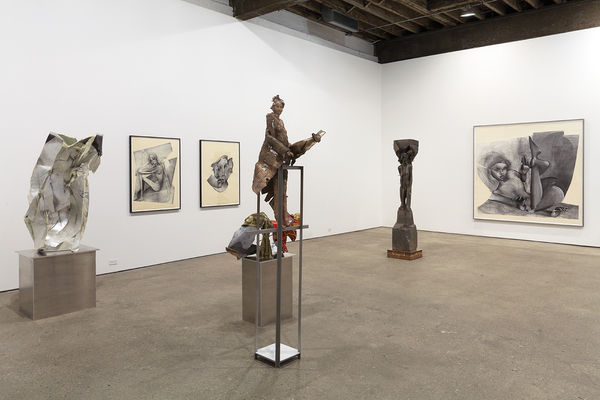 Installation view of Matthew Monahan's sixth solo show at Anton Kern Gallery, featuring sixteen sculptures, a set of drawings, two wall-mounted masks, and a single large figure in the back room. A few sculptures and drawings.