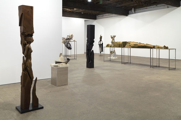 Installation view of Matthew Monahan's sixth solo show at Anton Kern Gallery, featuring sixteen sculptures, a set of drawings, two wall-mounted masks, and a single large figure in the back room. Many works shown.