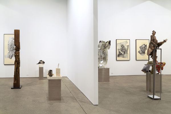 Installation view of Matthew Monahan's sixth solo show at Anton Kern Gallery, featuring sixteen sculptures, a set of drawings, two wall-mounted masks, and a single large figure in the back room. Many works featured.