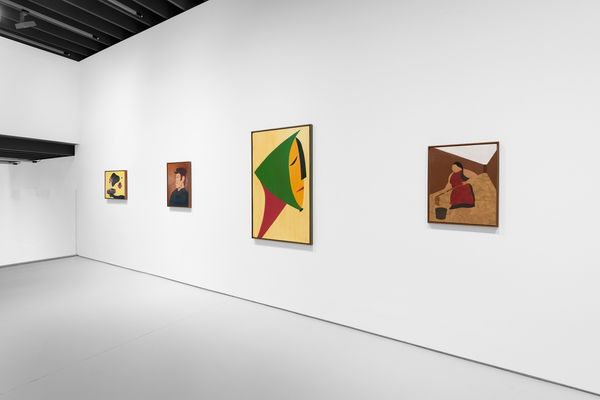 Foreshortened view that includes four paintings, and a dark architectural feature toward left side of image.