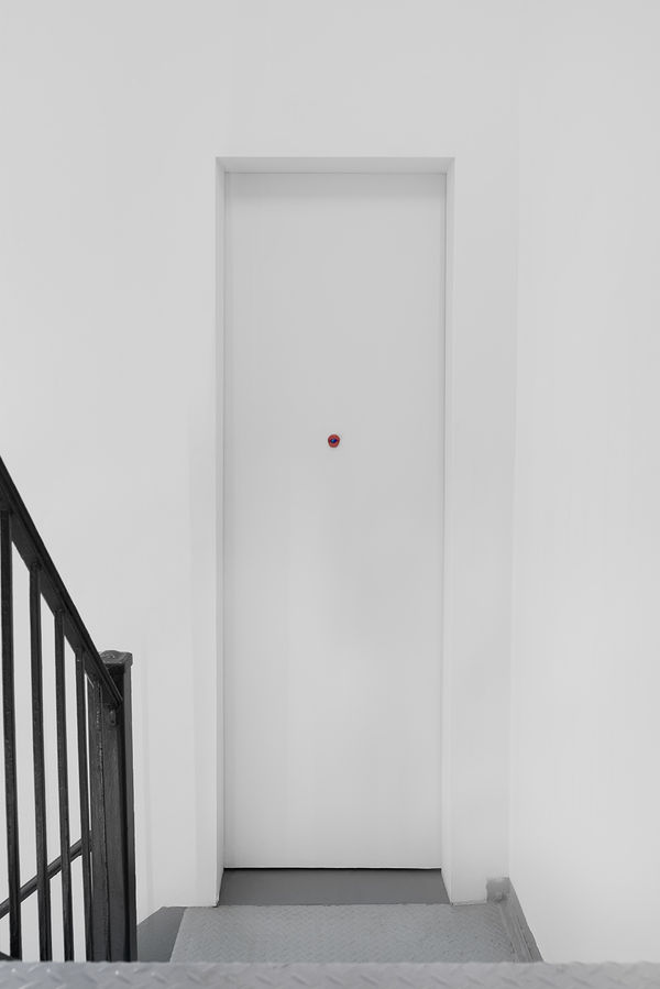 Installation view of the 2023 exhibition “Tondo” with view of white door, walls, and artwork on door.