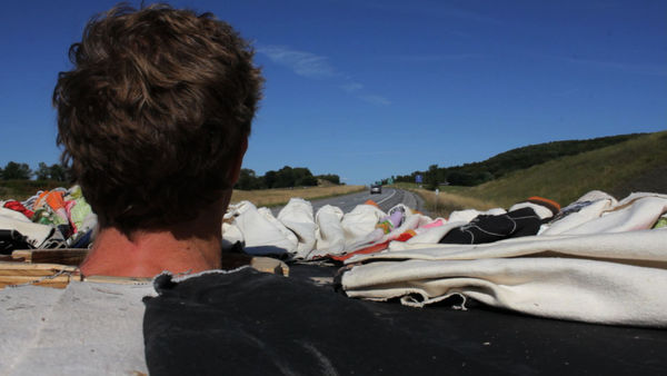 Back of man's head overlooking hills covered in waves of fabric