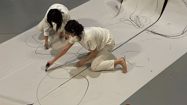Performance O, 2023. Drawing paper, marker, chalk, tape player, cassette, bagel, voice; 13:00. With Saskia Globig