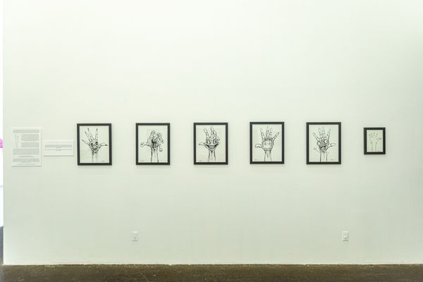 Black and white framed drawings by Alex Pardee, on a white wall