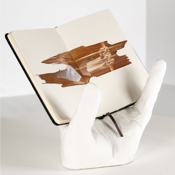 earth tone drawing in a notebook held up by a hand