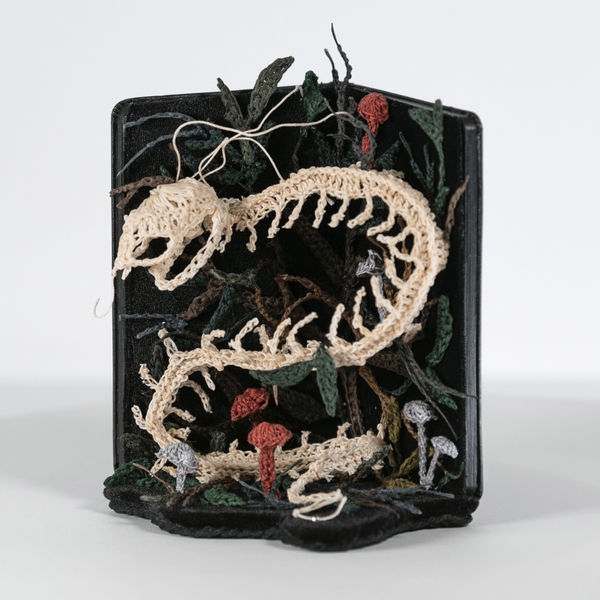 textile bone sculpture made inside of a moleskin notebook