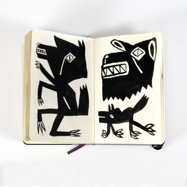 three angular black and white creatures drawn in a moleskin notebook