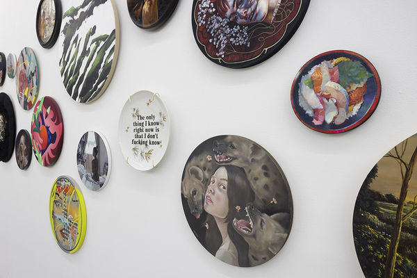 installation image of many round format artworks displayed on a white wall