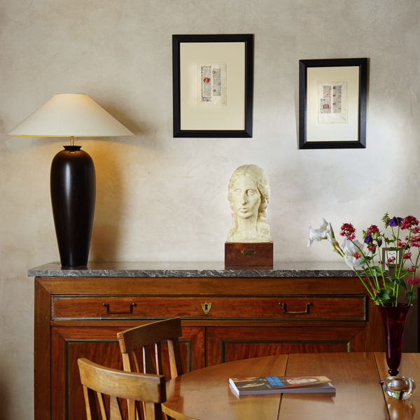 Interior view at La Gabrielle Fine Arts SA, Geneva, featuring a refined display of medieval and Renaissance art. A mahogany sideboard with marble top anchors the composition, adorned with a sleek black ceramic lamp and a classical marble portrait bust on