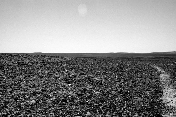 Ariel Yannay: The Mountain of God. A desert path and pale sun documenting the inseparable layers of cultures and myths intertwined in the stone.