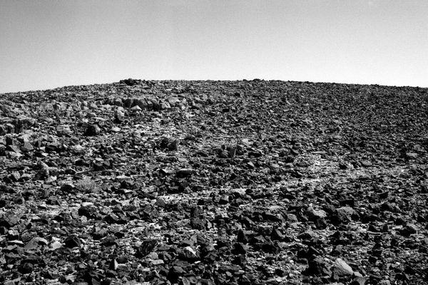 B&W photograph of a rocky slope at Mount Karkom by Ariel Yannay. Textures of stones bearing witness to tens of thousands of years of human passage.