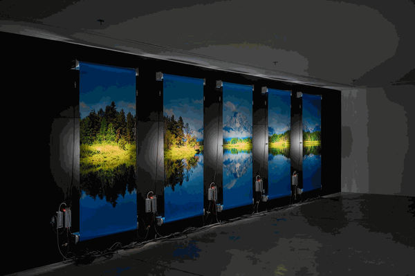 Clint Baclawski, "Departure," 2022. Scrolling lightbox kits, electronic ballasts, Latex prints, 2-foot LED bulbs, speaker wires, power cords, Stinger cable power supply, matte black wall.CLINT BACLAWSKI