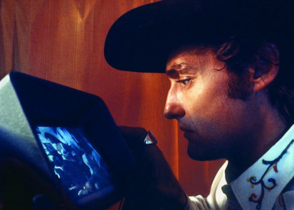 Color photograph of Dennis Hopper closely looking at a camera screen