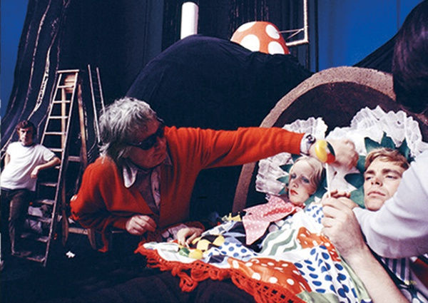 Color photograph of actors in bed on the set of a film