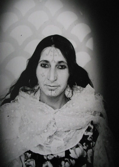1960s black & white portrait of Amazigh woman with facial tattoos, wearing white dress, in a photography studio