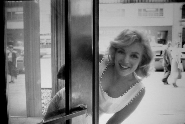 Black and white photograph of Marilyn Monroe peering around a door