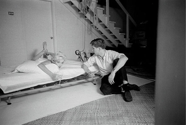 Black and white photograph of photographer Douglas Kirkland photographing Marilyn Monroe in bed