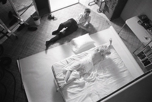 Black and white photograph of photographer Douglas Kirkland photographing Marilyn Monroe in bed