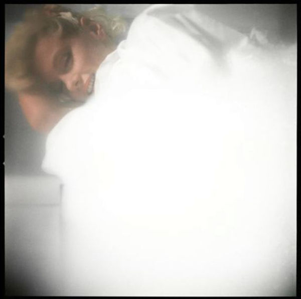 Carbon print of Marilyn Monroe from a high vantage point, wrapped in bedsheets on a bed