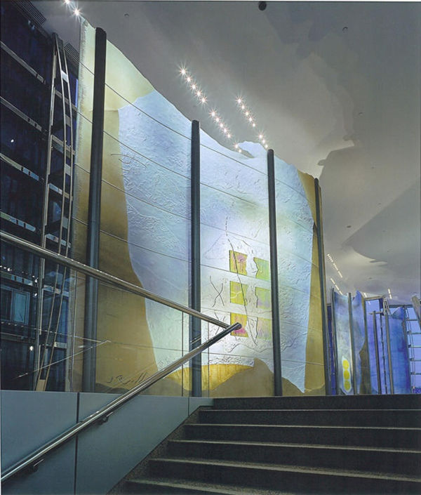 Large dichroic glass sculpture like an oversize modular screen (green, yellow, blue) with two people next to it