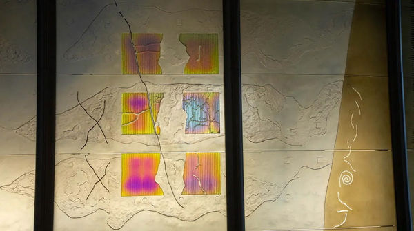 Detail of a large dichroic glass sculpture like an oversize modular screen (green, yellow, blue) 