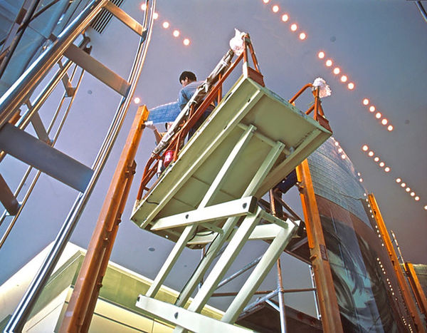 A man on a machine works on a large dichroic glass sculpture