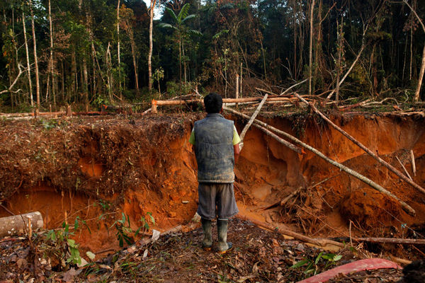 A gold miner stands above a ravine in the mining city of Lamal